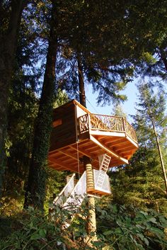 a tree house in the woods with stairs leading up to it's top deck