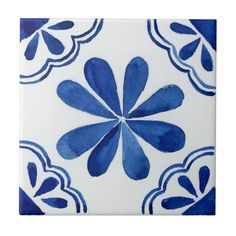 a blue and white tile with an ornate design on it's side, in the shape of a flower