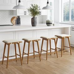 three stools in front of a white kitchen island with potted plant on it