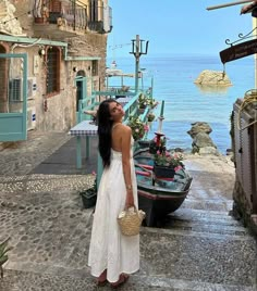 a woman standing in front of a boat looking at the water from an alley way