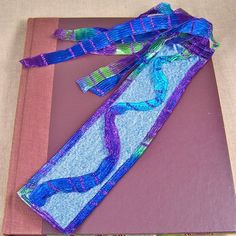 a purple book with blue and green ribbons on it sitting on top of a table