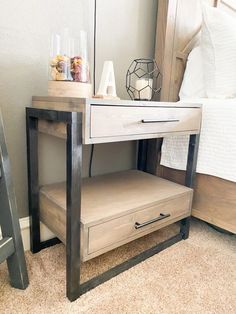 a night stand with two drawers and a lamp on it next to a bed in a bedroom