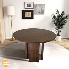 a round wooden table sitting on top of a white rug next to a potted plant