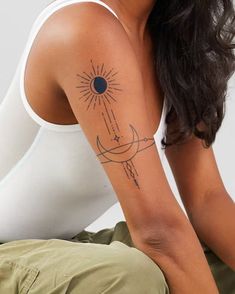 a woman with a sun and moon tattoo on her left arm, sitting in front of a white wall