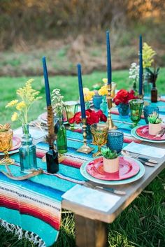 an outdoor table set with plates and candles