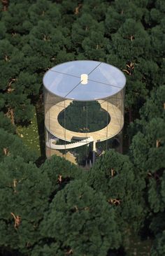 an aerial view of a building in the middle of a forest with trees around it