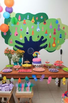 a table topped with lots of cakes and cupcakes next to a giant tree