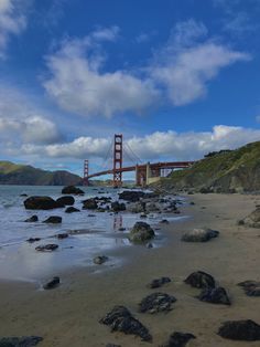 the golden gate bridge as seen from the beach with rocks and water in foreground