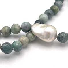 Imagine warm tropical water, dreamy green colors that change when the sun rises or sets. Imagine wearing a one of a kind piece of jewelry that gives you these beachy feels and more. Our Burmese aka multicolor Green Jade necklace makes a statement, at the beach, on vacation, or even an office. A single white Baroque pearl is the focal piece, and adds a simple, yet elegant charm. Not your everyday pearl necklace; this is sure to be a favorite for lovers of surf, sea and sand. Approximately 30 inch Elegant Green Necklace For Beach, Green Moss Agate Round Bead Necklaces, Green Moss Agate Round Bead Necklace, Unique Green Necklace For The Beach, Ocean-inspired Green Beaded Jewelry, Handmade Green Strand Jewelry, Spiritual Green Necklace For Beach, Artisan Green Necklace For The Beach, Artisan Green Necklace For Beach