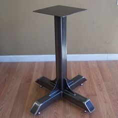 a metal table with four legs on a wooden floor