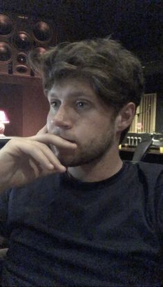 a man sitting in front of a wine glass with his hand on his chin and looking at the camera