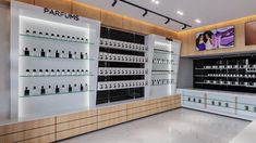 the inside of a perfume store with many bottles on shelves and two televisions above them