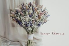 a bouquet of dried flowers sitting on top of a white cloth covered tablecloth next to a window