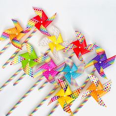 colorful paper pinwheels with polka dots and stripes on them are lined up against a white background