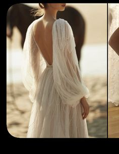 a woman in a white dress standing next to a brown horse on the beach with her back turned