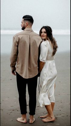 a man standing next to a woman on top of a beach