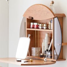 a wooden shelf with various items on it in front of a mirror and wall mounted light