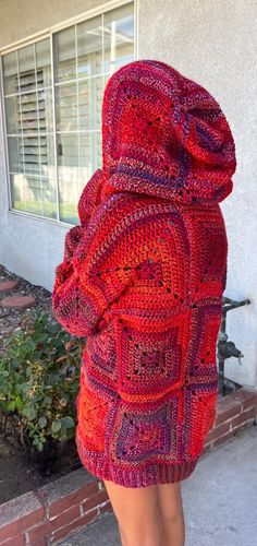 a woman in a red sweater is standing on the sidewalk with her back turned to the camera