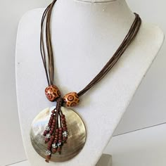 a necklace on a mannequin is adorned with brown bead and shell pendants