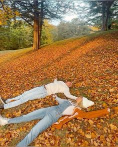 a man laying on the ground in leaves next to a woman with her head down