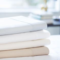 a stack of white sheets sitting on top of a bed next to a pillow case