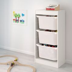 a toy train set sitting next to a white shelf with three bins on it