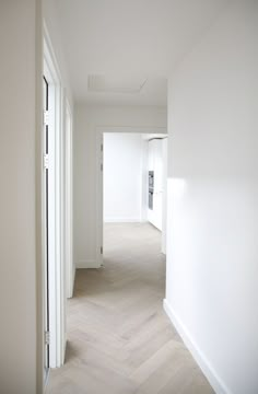 an empty hallway with white walls and wood floors