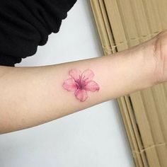 a woman's arm with a pink flower tattoo on it