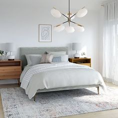 a bedroom with a bed, nightstands and two lamps hanging from the ceiling above it