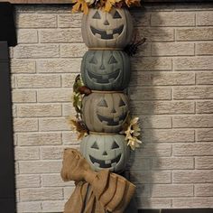 three pumpkins are stacked on top of each other in front of a fireplace with fall decorations