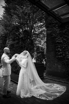 a man and woman standing next to each other in front of a building with trees