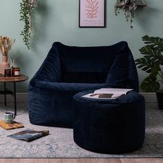 a living room filled with furniture and plants on top of a wooden floor next to a blue wall