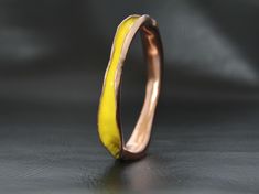 a yellow and pink ring sitting on top of a black table next to a gray wall