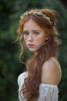 a woman with long red hair wearing a white dress and a gold headpiece on her head