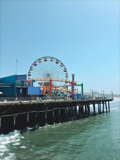 a ferris wheel sitting on top of a pier next to the ocean