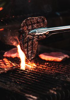 a steak being cooked on the grill with flames coming out of it's sides