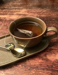 a cup of tea and spoon on a tray