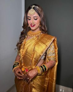 a woman wearing a gold sari and jewelry