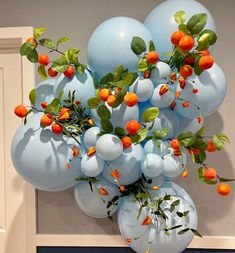 a bunch of blue balloons with oranges on them hanging from a wall in front of a door