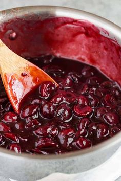 a wooden spoon in a pot filled with cranberry sauce on top of a table