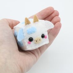 a hand holding a small stuffed animal in it's palm