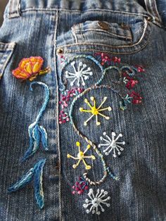 a pair of jeans with embroidered flowers on the back, and buttons attached to them