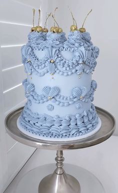 there is a blue cake with gold decorations on the top and bottom, sitting on a silver platter