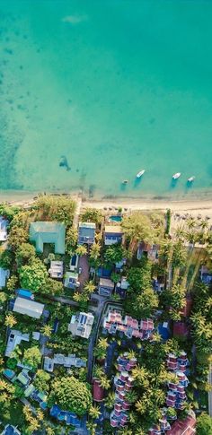 an aerial view of a beach with houses and trees in the foreground, surrounded by blue water