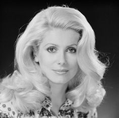 a woman with long blonde hair and blue eyes posing for a studio photo in front of a dark background