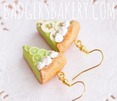 two slices of pie with white frosting and limes on them are dangling from gold earwires