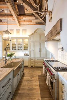 a kitchen with white cabinets and wood floors, an island in the middle is surrounded by deer heads