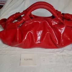 Loewe Top Handled Red Patent Leather Bag. Dual Red Spiral Handles Silvertone Hardware Spacious Interior W/ Interior Pockets Recessed Zipper For Protection Approximate Measurements: 17" X 12.5" X 7" Includes Original Certificate Of Authenticity & Care Card. Excellent Condition With No Real Callouts. Some Rubbing Of Leather Loop. May Have Minor Scratches On Hardware Or Tiny Rubbing, As Is Normal For Pre-Loved Bags. See Photos As They Are Part Of The Description. Designer Shoulder Bag With Rolled Handles For Errands, Red Double Handle Shoulder Bag With Rolled Handles, Red Shoulder Bag With Rolled Handles For Shopping, Designer Shoulder Bag With Rolled Handles, Elegant Red Shoulder Bag With Rolled Handles, Red Leather Bag With Rolled Handles, Red Shoulder Bag With Rolled Handles For Daily Use, Red Shoulder Bag With Rolled Handles, Designer Red Pouch Satchel