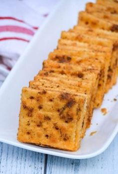 cheesy crackers on a white plate next to a red and white striped towel