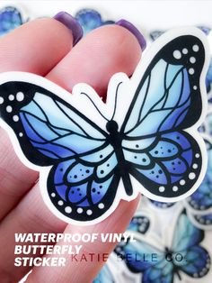 a hand holding a blue and white butterfly sticker